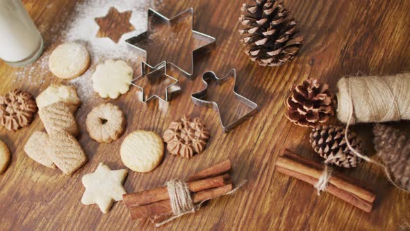 Video of christmas decorations with an assortment of cookies and glass of milk on wooden background