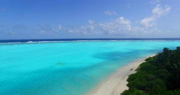 Wide angle flying clean view of a paradise sunny white sand beach and aqua blue ocean background