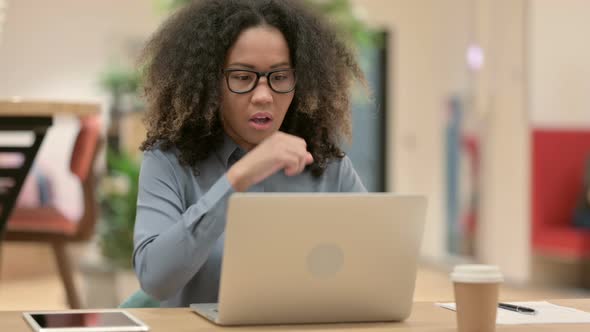 Young African Woman with Laptop Coughing