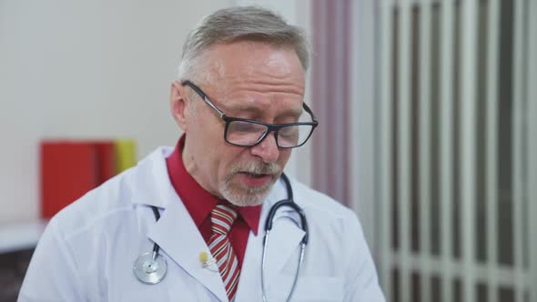 Senior doctor talking to camera. Talking doctor during online video chat with patient