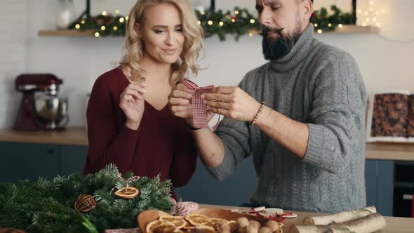 Blonde woman teaching men how to make Christmas bow. Shot with RED helium camera in 8K