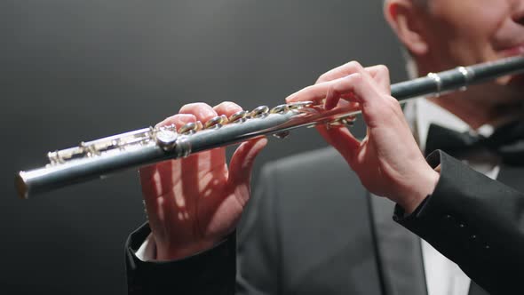 Musician is Playing Flute in Opera House or Modern Music Hall Closeup of Male Hands with Flute