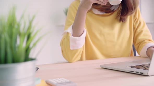 Asia business woman writing notebook document finance and calculator in home office.