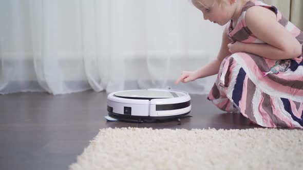 Cute Little Girl Independently Turns on and Maintains the Robot Vacuum Cleaner