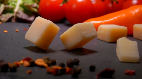 Hard Cheese Cubes Fall on Black Surface with Pepper