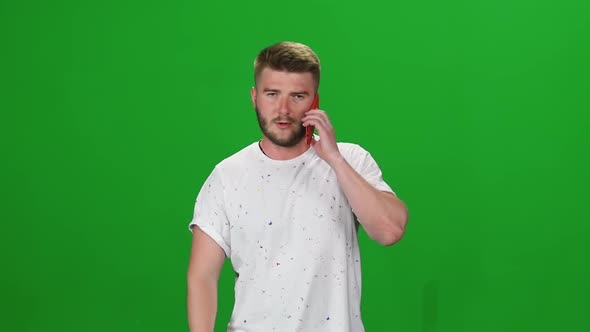 Portrait Bearded Guy Calmly Walking and Talking on the Mobile Phone on Greenscreen. Chroma Key