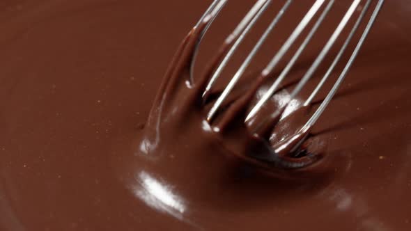 Slow Motion Mixing Stirring Premium Dark Melted Chocolate with a Whisk Process of Making Sweets