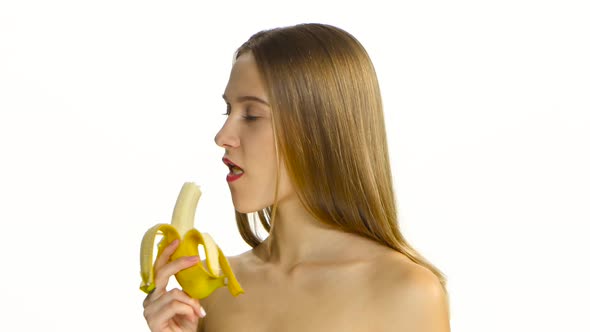 Girl with Braces Eating a Big Banana. White. Closeup