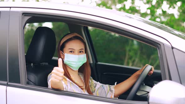 The female driver wearing surgical mask felt confident and gesturing thumbs up while traveling