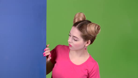 Girl Peeks Out From Behind a Blue Board and Shows a Ok. Green Screen. Slow Motion