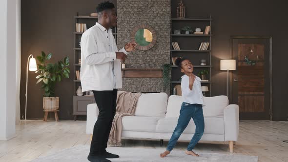 Happy Two Active African American Family Dancing in Living Room Carefree Adult Father Man and Cute