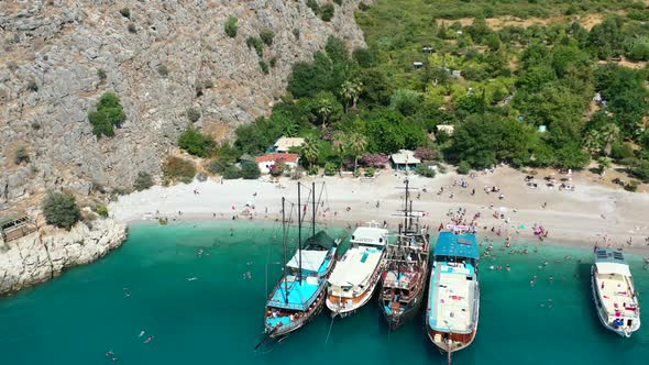 aerial drone circling pirate cruise ships anchored on the beach at Butterfly Valley in Fethiye Turke