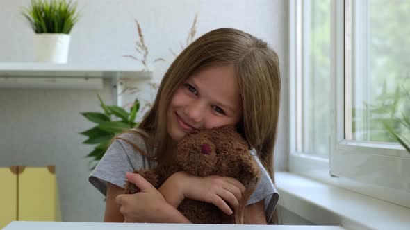 Portrait of a Little Girl with a Teddy Bear Looking at Camera