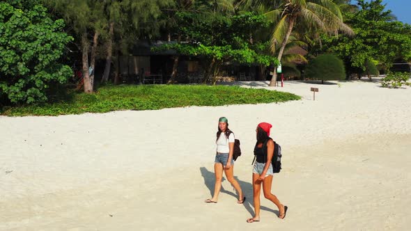 Beautiful ladies happy and smiling on tranquil seashore beach adventure by blue green lagoon and whi