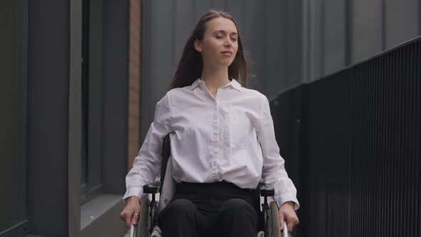 Medium Shot Portrait of Young Gorgeous Disabled Caucasian Woman Sitting in Wheelchair Looking at