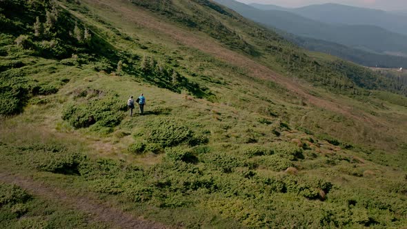 Aerial Drone View of a Couple of Travelers Man and Woman with Backpacks Walking Together on the