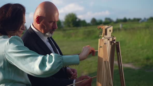 Side View Happy Man and Woman Painting Outdoors in Slow Motion at Background of Beautiful Landscape