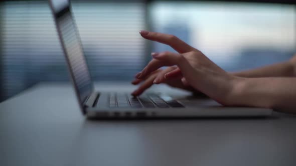 Close-up hands of unrecognizable business woman typing on laptop sitting at desk in office