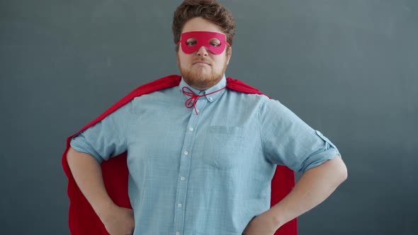Portrait of Man in Super Hero Costume Red Cape and Mask on Gray Background