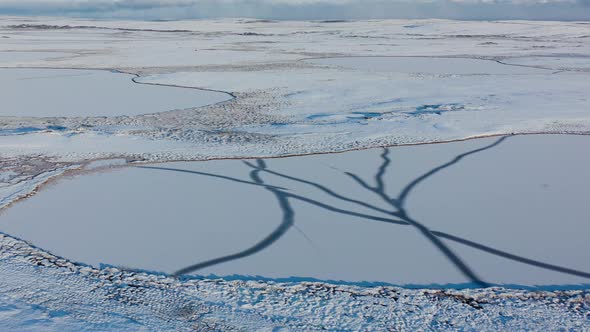 Aerial view of of the snow covered valley and the frozen lake. Arctic landscape.