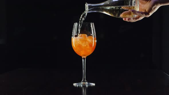 Close Up Bartenders Hands Pouring Prosecco in Wine Glass with Ice, Mixing Cocktail with Orange Juice