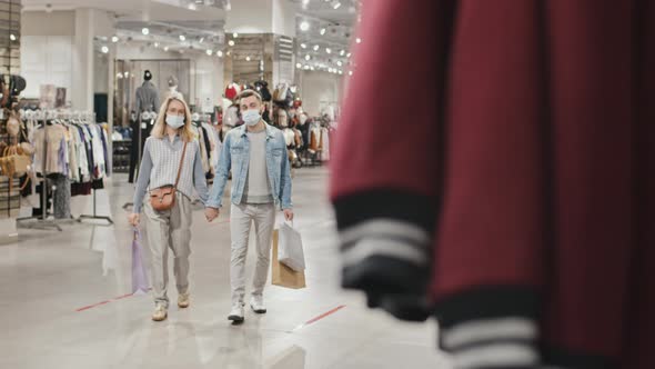 Young Couple In Face Masks Shopping At Clothing Store