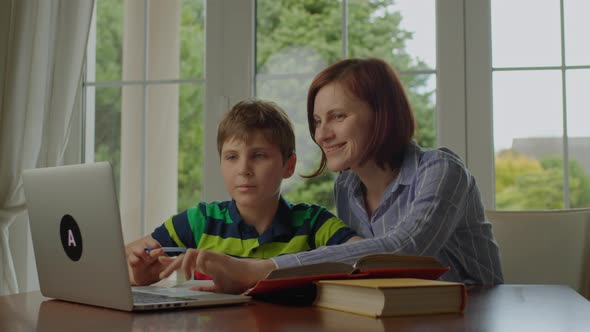 Young Adult Mother Making Online Homework with School Child at Home