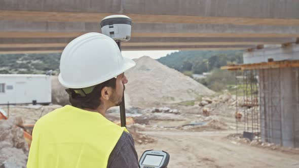 Construction engineer working with GPS equipment on a large highway construction site