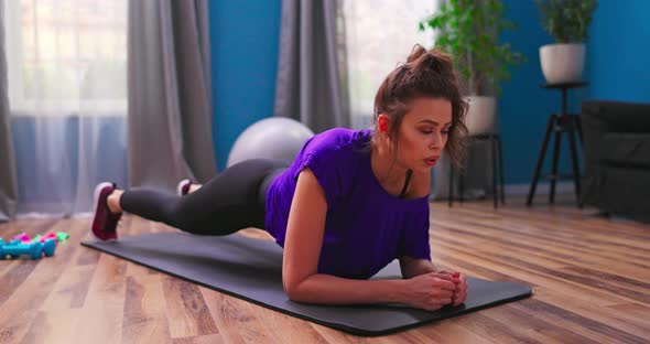 Young Beautiful Athletic Girl in Leggings and Top Makes an Exercise Plank