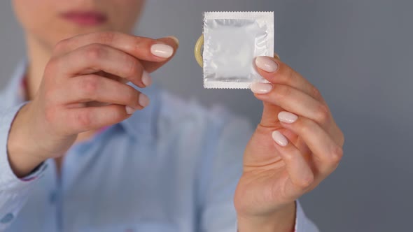 Female Hands Demonstrating Condom Before Camera, Safe Sex, Contraception