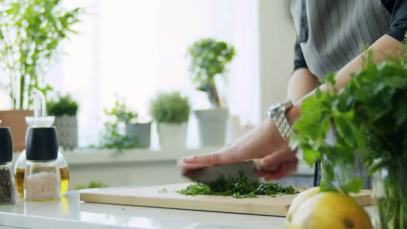 Woman cutting parsley on wooden board