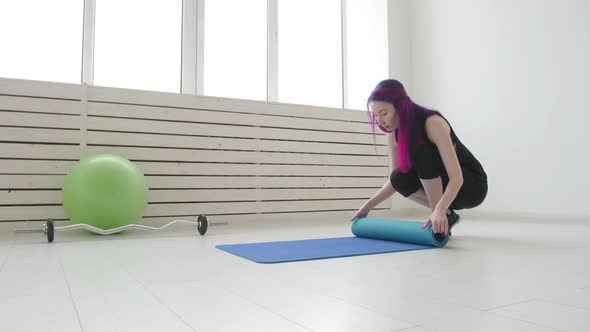 Concept of Sports and Health and Relaxation. Young Woman with a Yoga Mat and Exercises in an