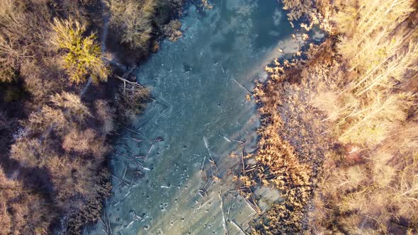 Aerial view on frozen lake in sunset wintry forest