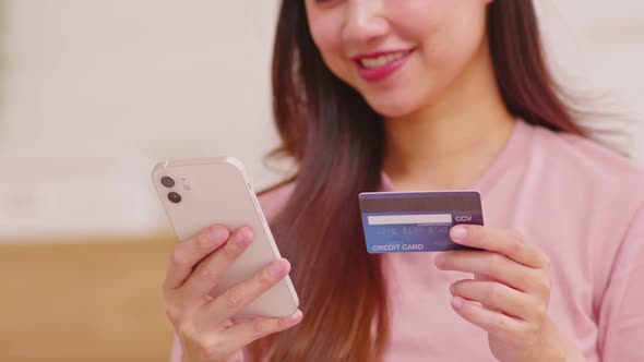 Close up Asian young woman using credit card for pay online shopping on mobile phone