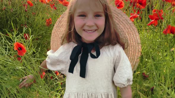 Happy girl in a field of blooming red poppies. Leisure in nature. Enjoying