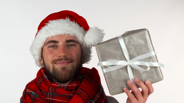 Handsome Bearded Man in Christmas Hat Smiling, Holding Up a Present