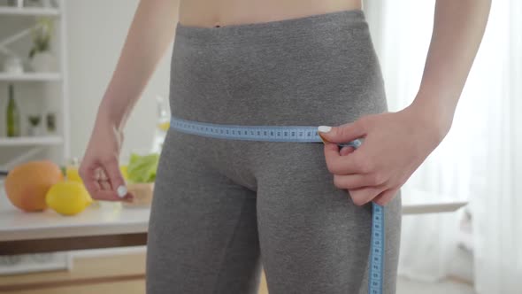 Close-up of Young Woman Measuring Hips with Tape