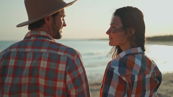 A Man Wearing a Hat and Beautiful Asian Woman Kissing on Sea Beach at Sunset