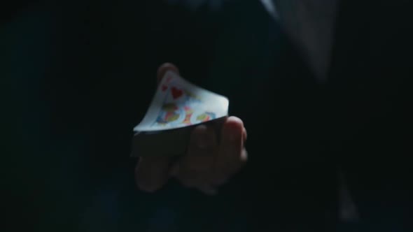 Close-up of the Hands of a Dressed Magician Performing a Card Trick. Cards Fly Into the Camera From