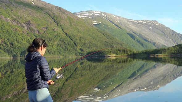 Woman Fishing on Fishing Rod Spinning in Norway