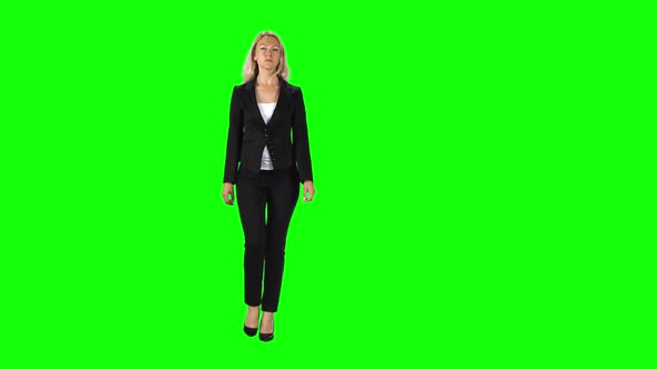 Blonde Girl in a Black Suit, White Blouse and High-heeled Shoes Going Against a Green Screen.