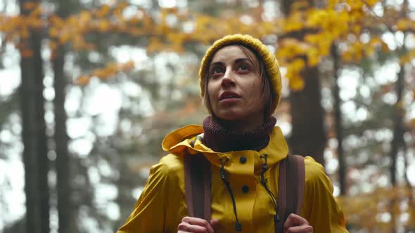 Close Up Portrait of Pretty Inspired Young Woman Hiker with Backpack Wearing Bright Yellow Raincoat