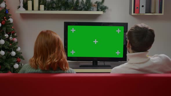 A Couple Watches Green Screen TV Mockup Sitting on Sofa in Living Room Together.