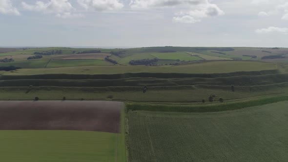 Aerial tracking upward and forward with Maiden Castle at the centre of interest. like skies, sea in