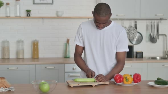Healthy African Man Cutting Vegetables in Kitchen