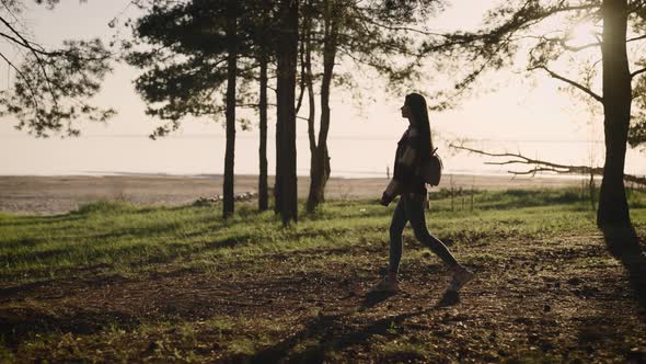 Beautiful Young Hipster Woman in a Shirt Walking Through a Picturesque Pine Forest