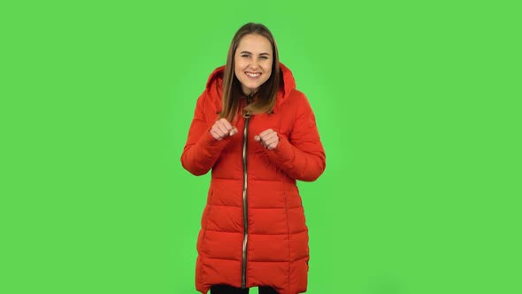 Lovely Girl in a Red Down Jacket Is Dancing Funny. Green Screen