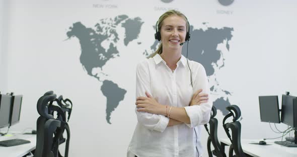 Beautiful Young Operator Woman Standing and Wearing Headset at the Bright Office Space
