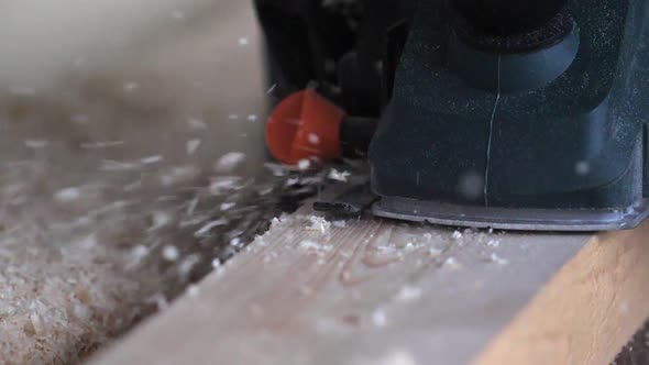 Man Shaving Wooden Plank with Electrical Hand Planer