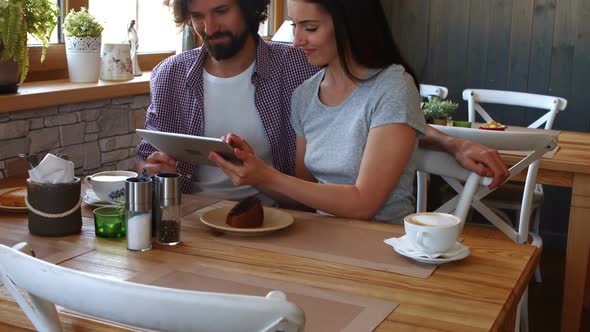 Couple using digital tablet in cafe